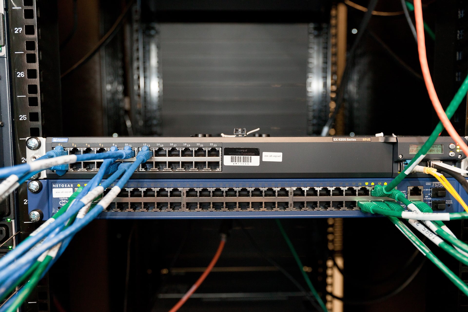 Network switches in a server rack with blue and green patch cables